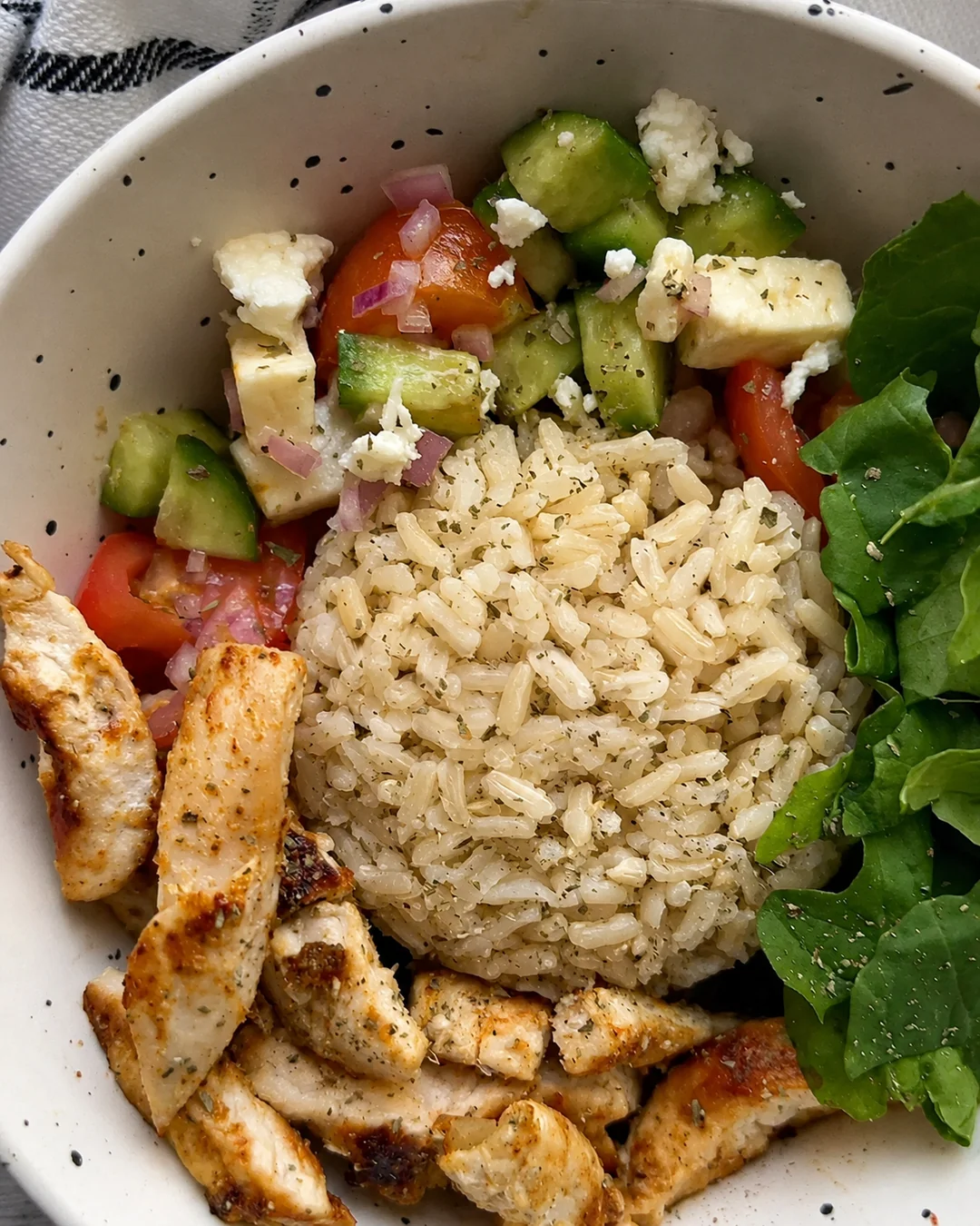 Bowl de pollo a la plancha con arroz integral, ensalada de pepino, tomate y queso feta, receta saludable de MAKEITGRAIN