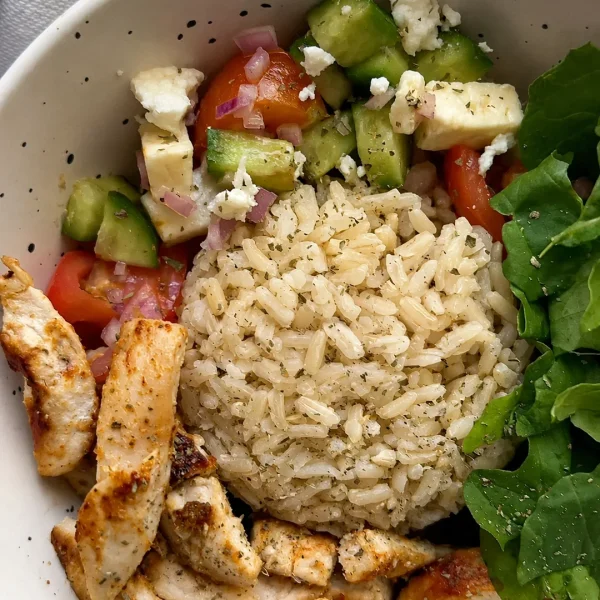 Bowl de pollo a la plancha con arroz integral, ensalada de pepino, tomate y queso feta, receta saludable de MAKEITGRAIN